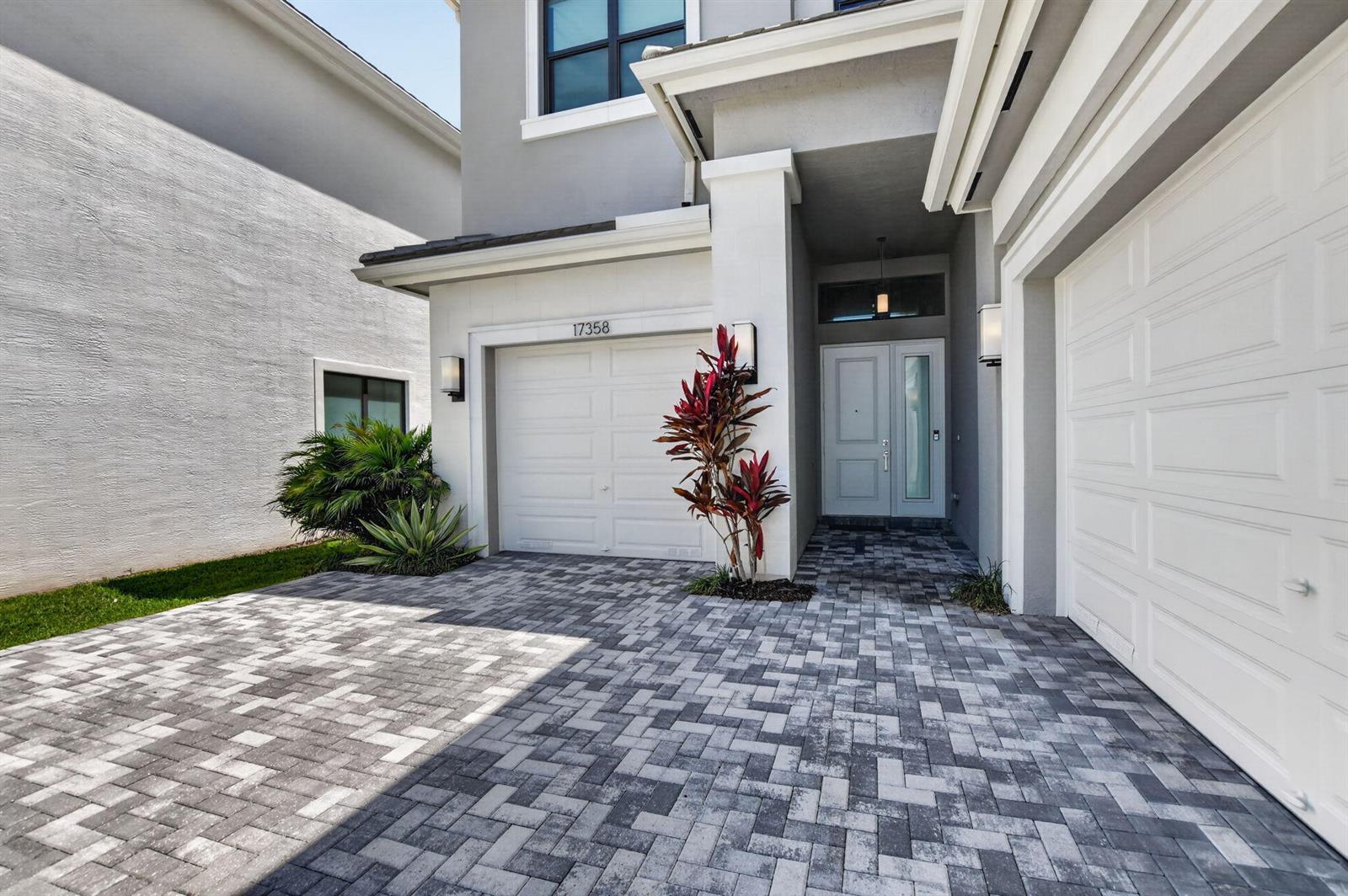 A two-story house exterior features a paved driveway, two garage doors, and a front entrance — 17358 Santaluce Manor, Boca Raton FL 33496, BOCA RATON, FL