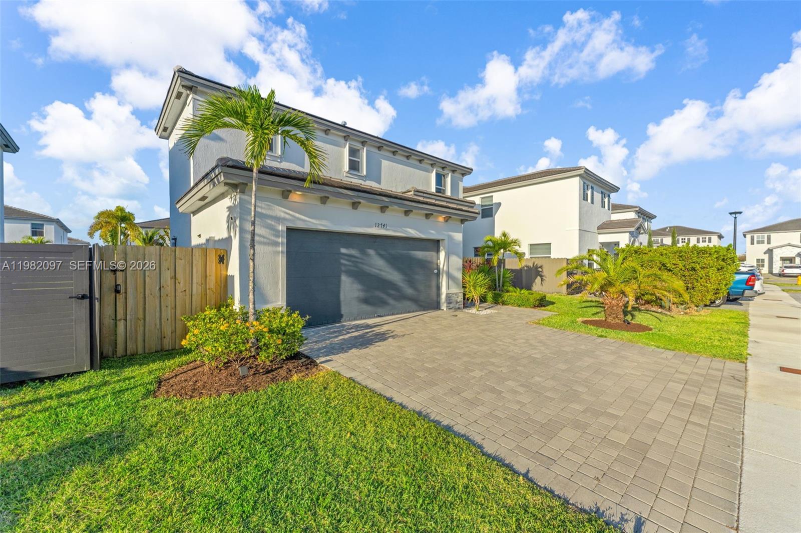 A two-story house features a gray garage, a paved driveway, and a wooden fence — 12741 SW 213th Ter, Miami FL 33177, MIAMI, FL