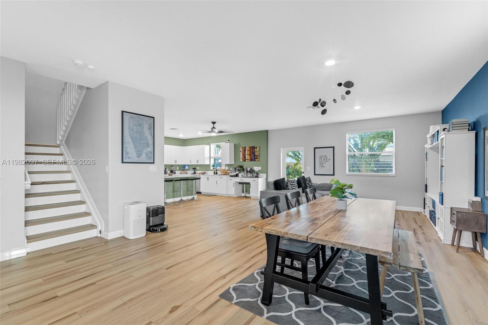 An open-concept living area features a dining space, kitchen with green walls, and staircase — 12741 SW 213th Ter, Miami FL 33177, MIAMI, FL