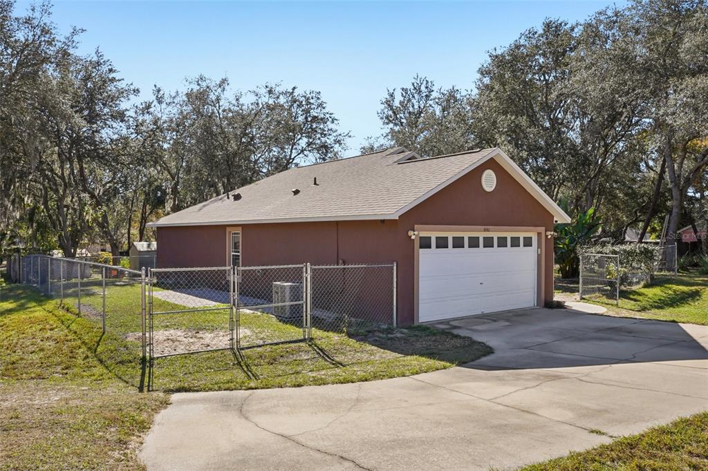 A brown house with a white garage door and a chain-link fence in the yard — 4542 LEMON STREET, LADY LAKE, FL