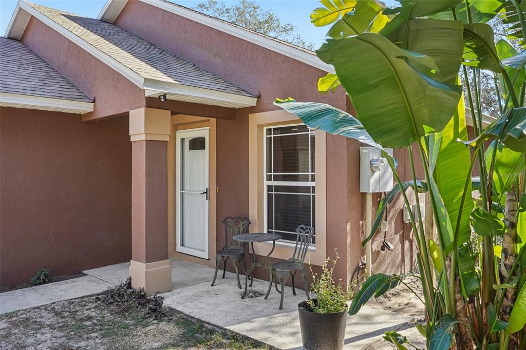A brown stucco house exterior features a small concrete patio with a bistro set — 4542 LEMON STREET, LADY LAKE, FL