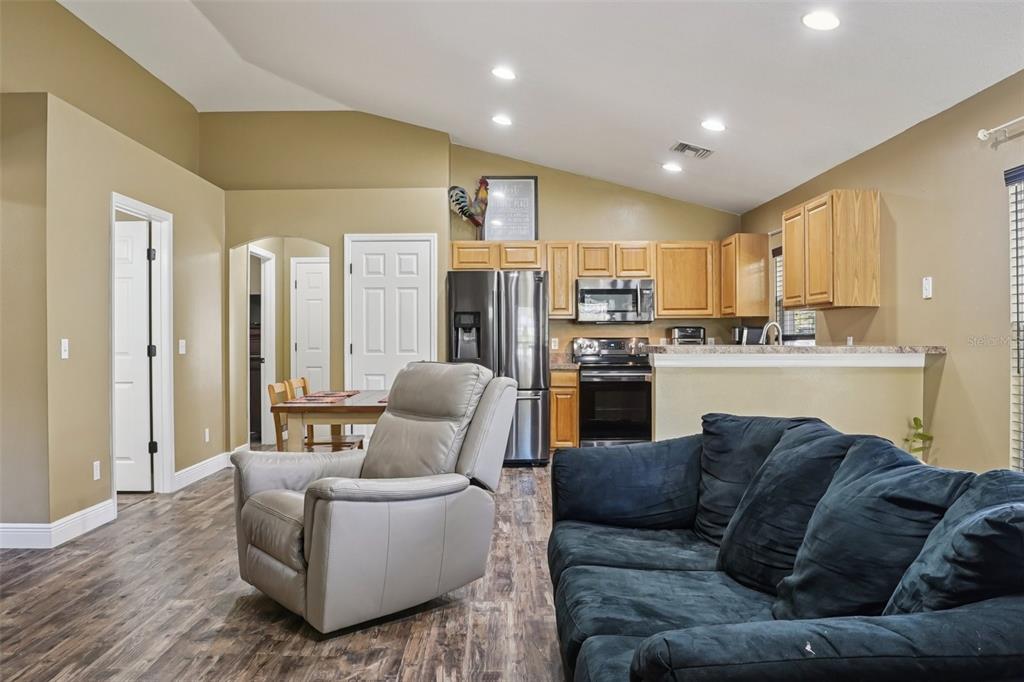 A living room with wood-look flooring opens to a kitchen featuring light wood cabinets — 4542 LEMON STREET, LADY LAKE, FL