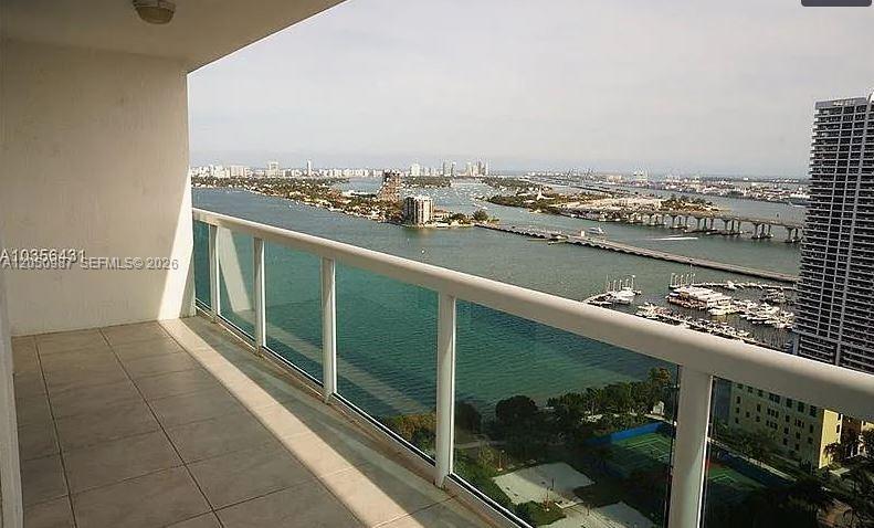 A high-rise balcony with a glass railing overlooks a bay, bridge, and city skyline — 1800 N Bayshore Dr # 3014, Miami FL 33132, MIAMI, FL