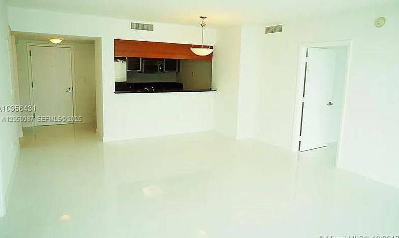 An interior view shows a white-floored living area with a kitchen pass-through and two doorways — 1800 N Bayshore Dr # 3014, Miami FL 33132, MIAMI, FL