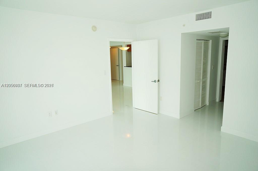 A bright, empty room features white walls, glossy white tile flooring, and two doorways — 1800 N Bayshore Dr # 3014, Miami FL 33132, MIAMI, FL