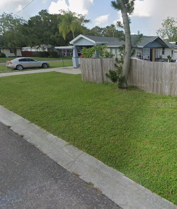 A single-story house with a wooden fence and a parked car in the driveway — 6500 HOBSON STREET NE, ST PETERSBURG, FL