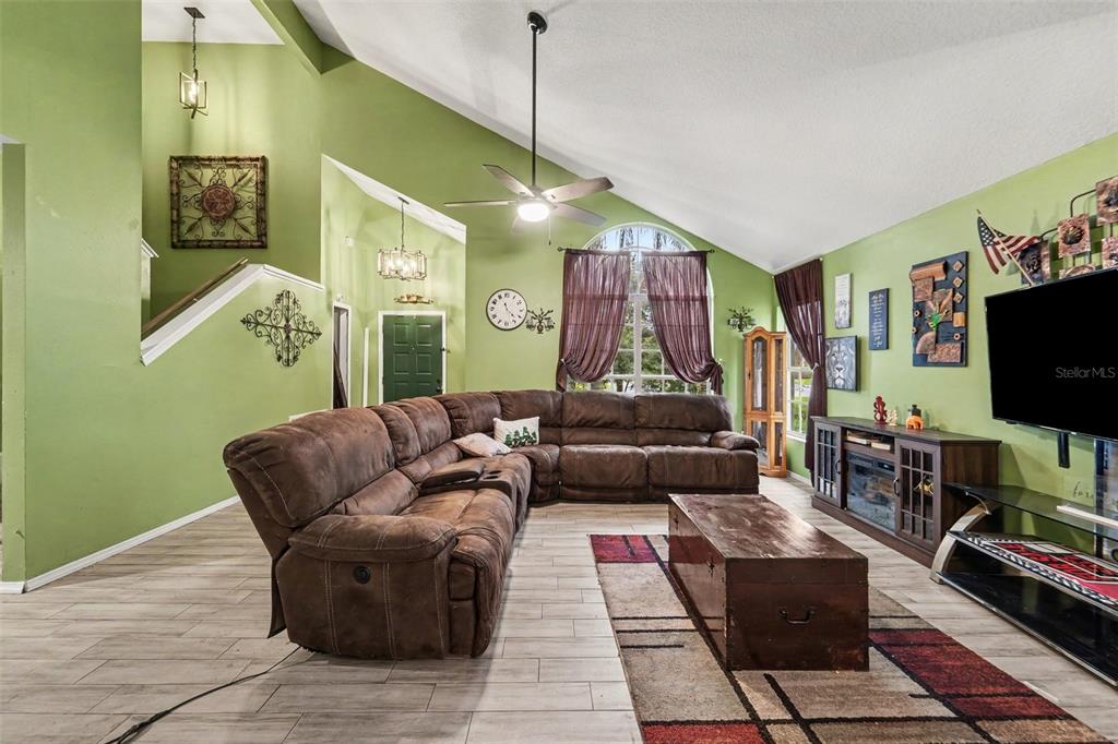 A living room features a large brown sectional sofa, vaulted ceilings, and green walls — 2405 ABALONE BOULEVARD, ORLANDO, FL