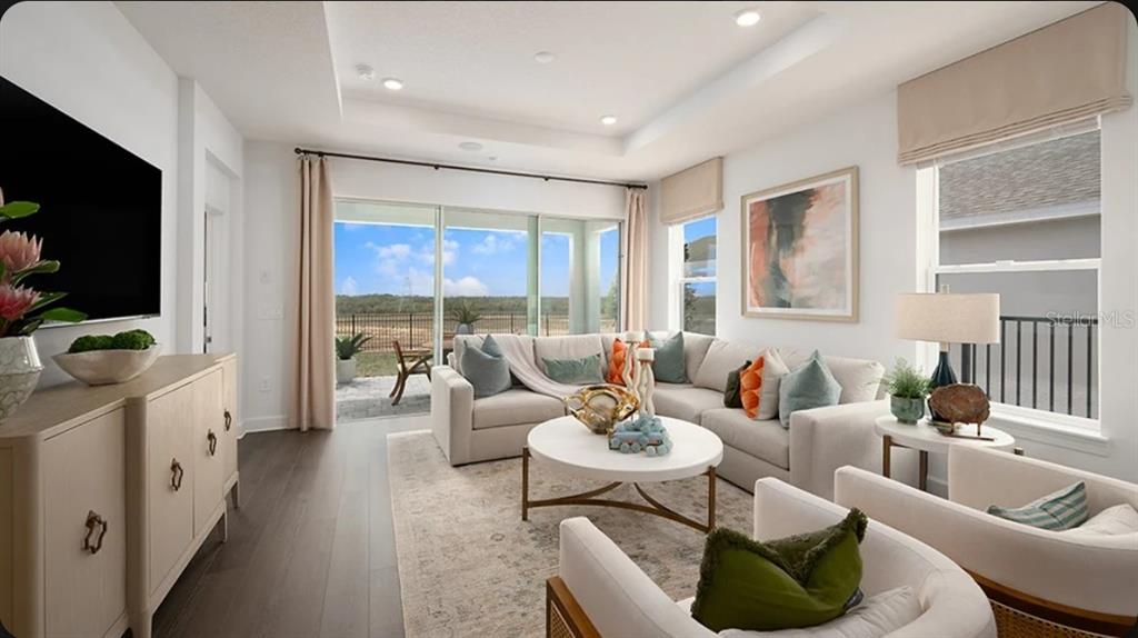 A bright living room features a sectional sofa, two armchairs, and sliding doors to a patio — 11279 SILVER TRUMPET LOOP, WINTER GARDEN, FL