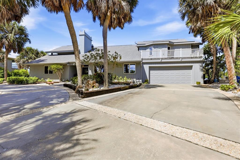 A gray two-story house with a two-car garage, a balcony, and several palm trees — 750 N MANASOTA KEY ROAD, ENGLEWOOD, FL