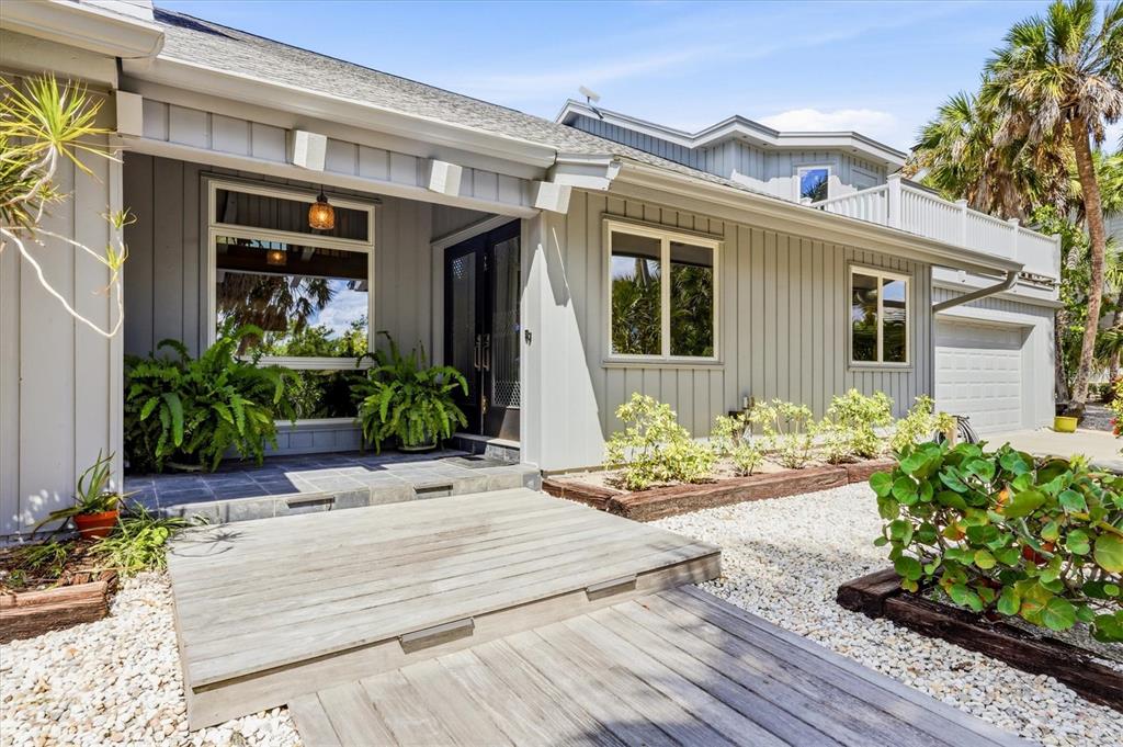 A gray house with vertical siding features a wooden deck leading to the front entrance — 750 N MANASOTA KEY ROAD, ENGLEWOOD, FL
