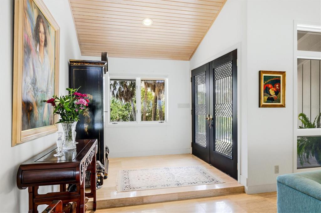 An entryway features a raised stone floor, a wood-paneled ceiling, and double black-framed glass doors — 750 N MANASOTA KEY ROAD, ENGLEWOOD, FL