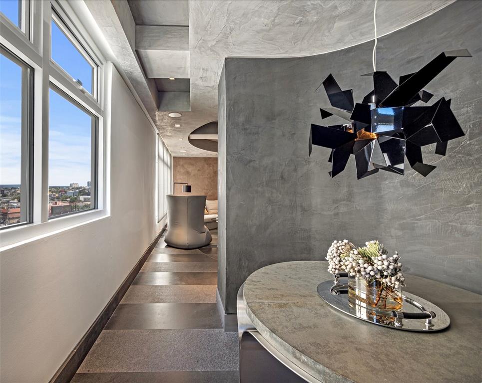 A modern hallway features a textured gray wall, a geometric pendant light, and city views — 1800 MCLEARY UNIT PH 2, SAN JUAN, PR