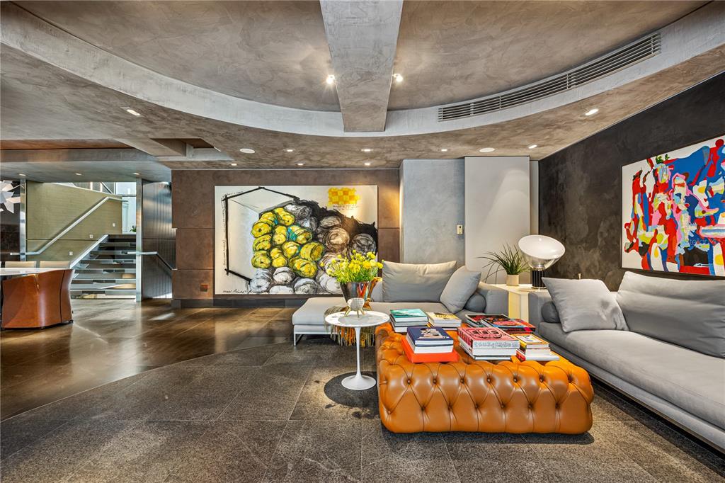 A modern living room features a tufted orange ottoman, grey sofas, and large abstract art — 1800 MCLEARY UNIT PH 2, SAN JUAN, PR