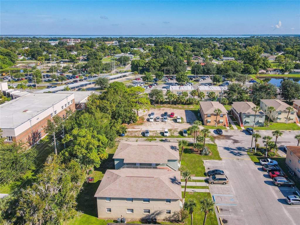 An aerial view shows apartment buildings, a parking lot, and surrounding trees under a blue sky — 714 MICHIGAN COURT UNIT 4, ST CLOUD, FL