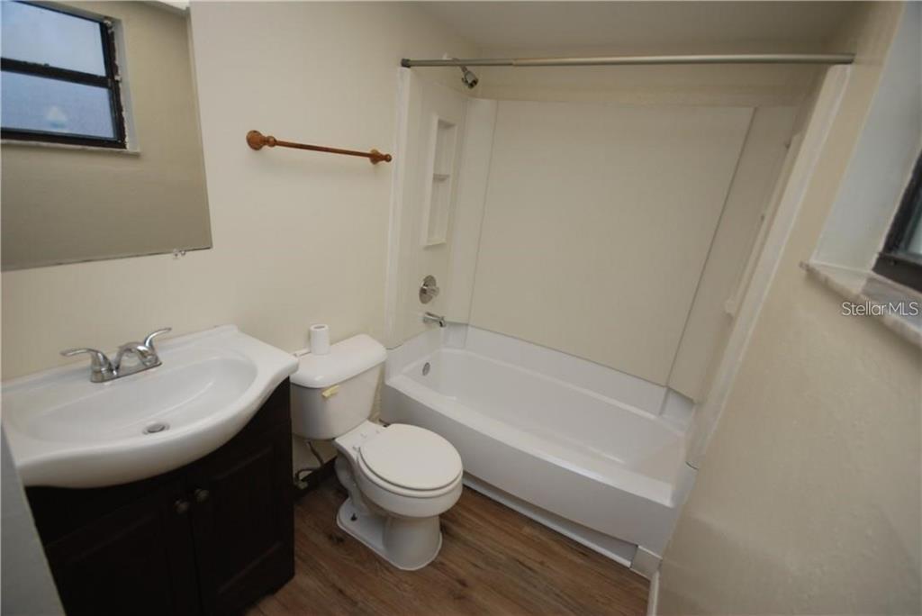 A bathroom features a dark wood vanity, a white toilet, and a shower-tub combination — 1254 E 113TH AVENUE UNIT C115, TAMPA, FL