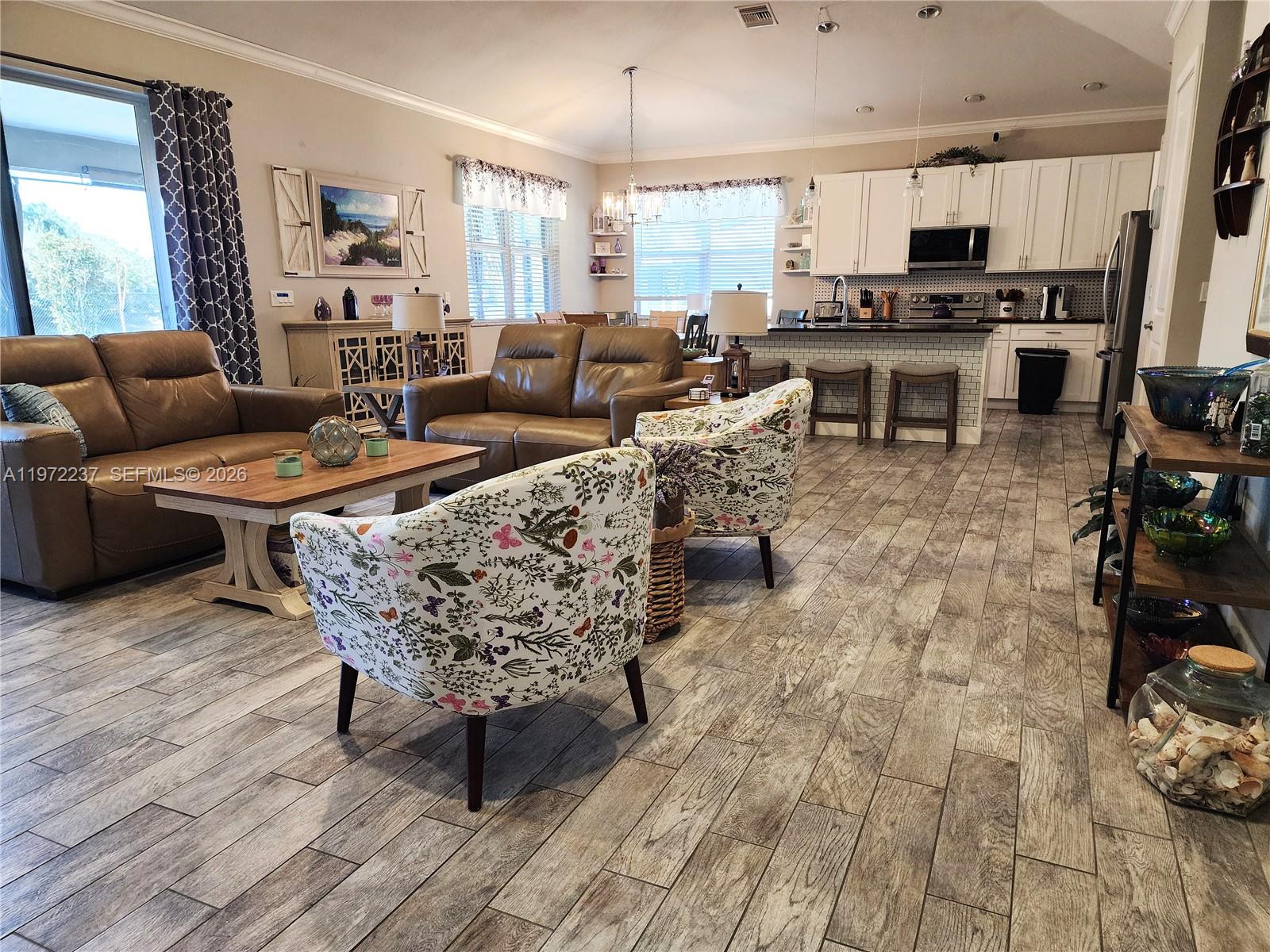 An open-concept living room and kitchen feature wood-look tile flooring and leather furniture — 108 Oak Knolls Circle, Sebring FL 33876, SEBRING, FL