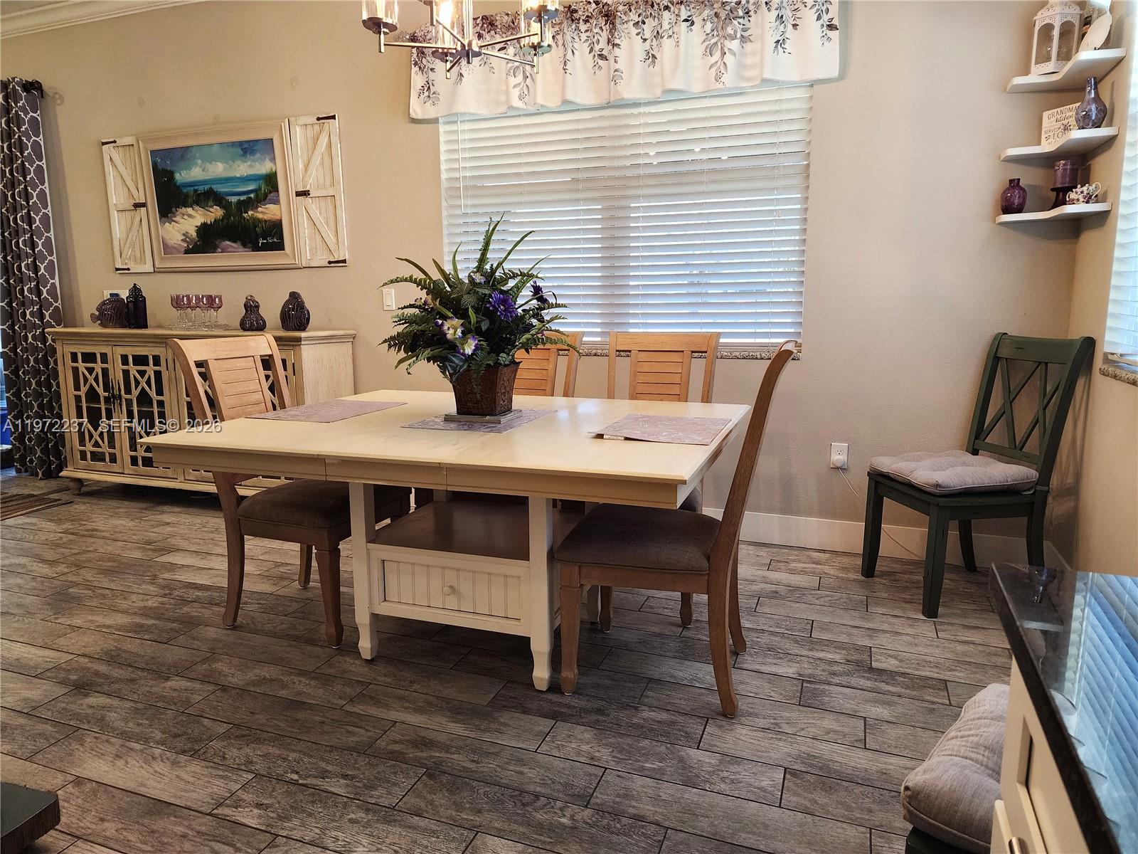 A dining room features a light-colored wooden table, chairs, and a sideboard on wood-look flooring — 108 Oak Knolls Circle, Sebring FL 33876, SEBRING, FL