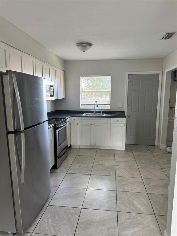A kitchen with white cabinets, stainless steel appliances, and light-colored tile flooring — 1112 MARTIN STREET UNIT C, HAINES CITY, FL