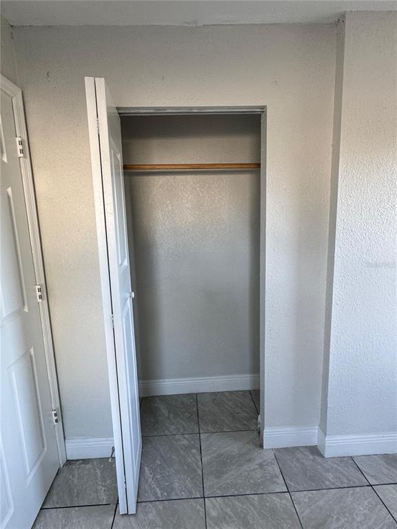 A closet with a wooden rod and white bifold doors sits in a tiled room — 1112 MARTIN STREET UNIT C, HAINES CITY, FL