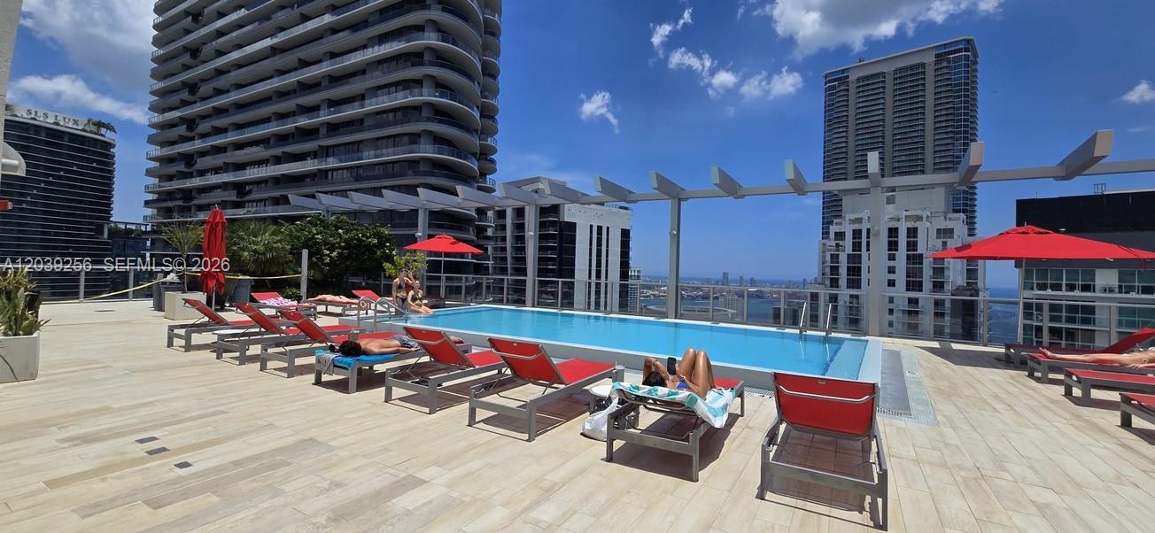 An outdoor rooftop swimming pool surrounded by lounge chairs and umbrellas with city skyline views — 1100 S Miami Ave # 3808, Miami FL 33130, MIAMI, FL