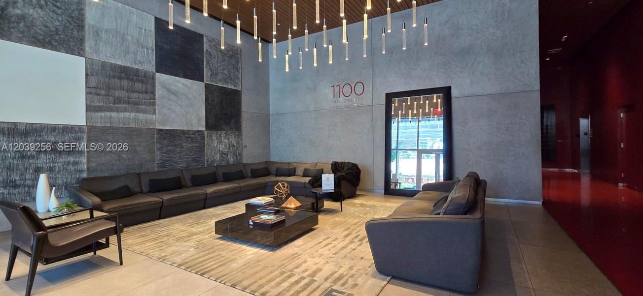 A modern lobby features a large sectional sofa, a coffee table, and hanging pendant lights — 1100 S Miami Ave # 3808, Miami FL 33130, MIAMI, FL
