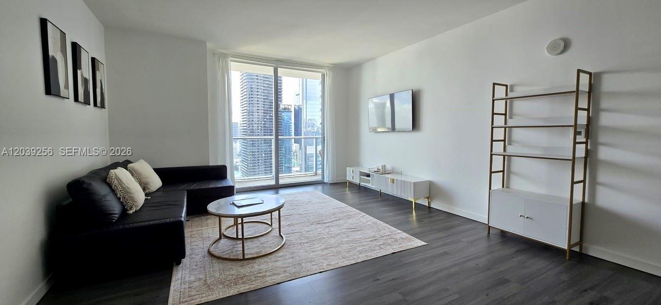A living room features a black sectional sofa, a coffee table, and a tall shelving unit — 1100 S Miami Ave # 3808, Miami FL 33130, MIAMI, FL
