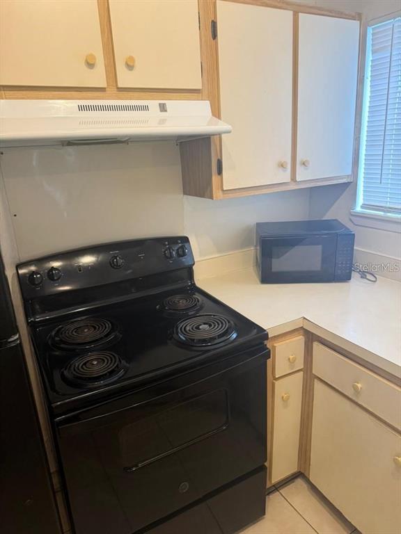 A kitchen features a black electric stove, white cabinets, and a countertop microwave — 1972 LAKE ATRIUMS CIRCLE UNIT 187, ORLANDO, FL