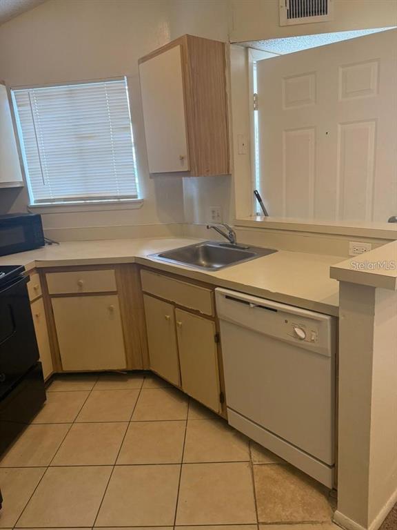 A kitchen with light-colored cabinets, a stainless steel sink, a dishwasher, and tiled flooring — 1972 LAKE ATRIUMS CIRCLE UNIT 187, ORLANDO, FL