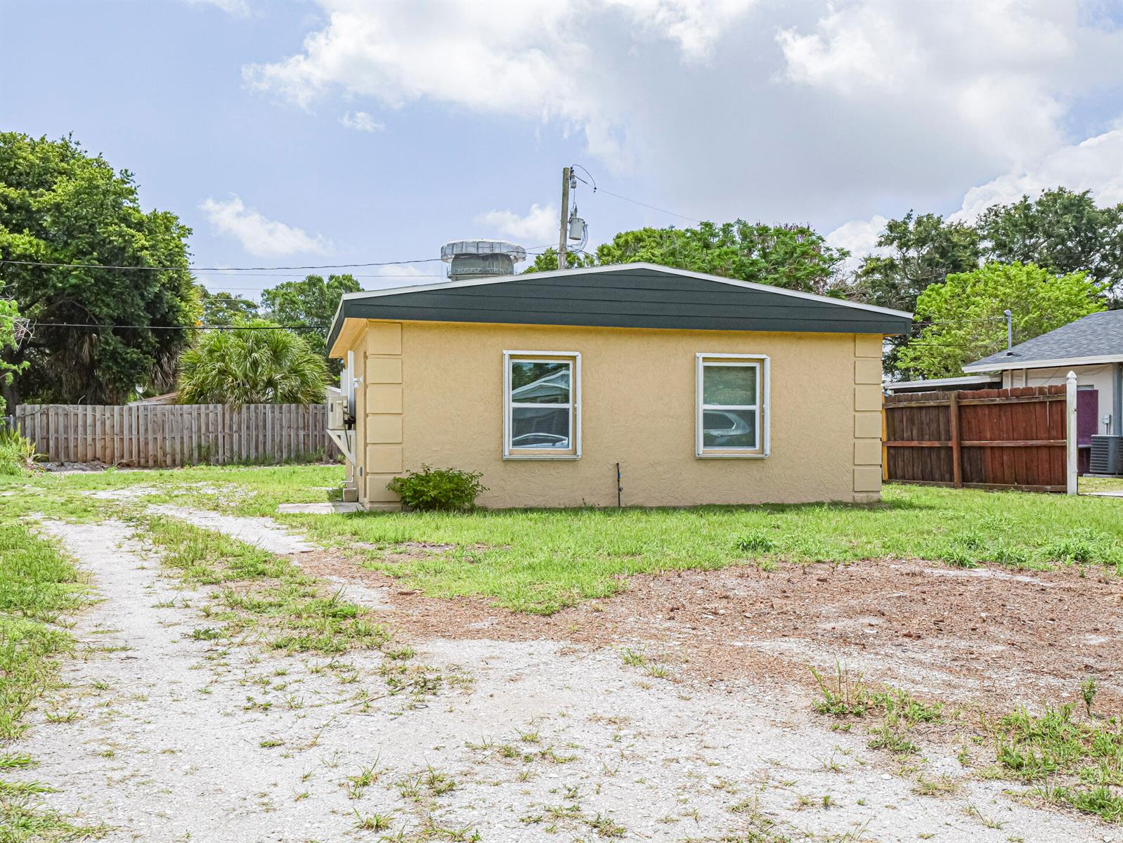 A small, yellow, single-story house with a dark roof sits on a gravel lot — 4716 29th Avenue, Vero Beach FL 32967, VERO BEACH, FL