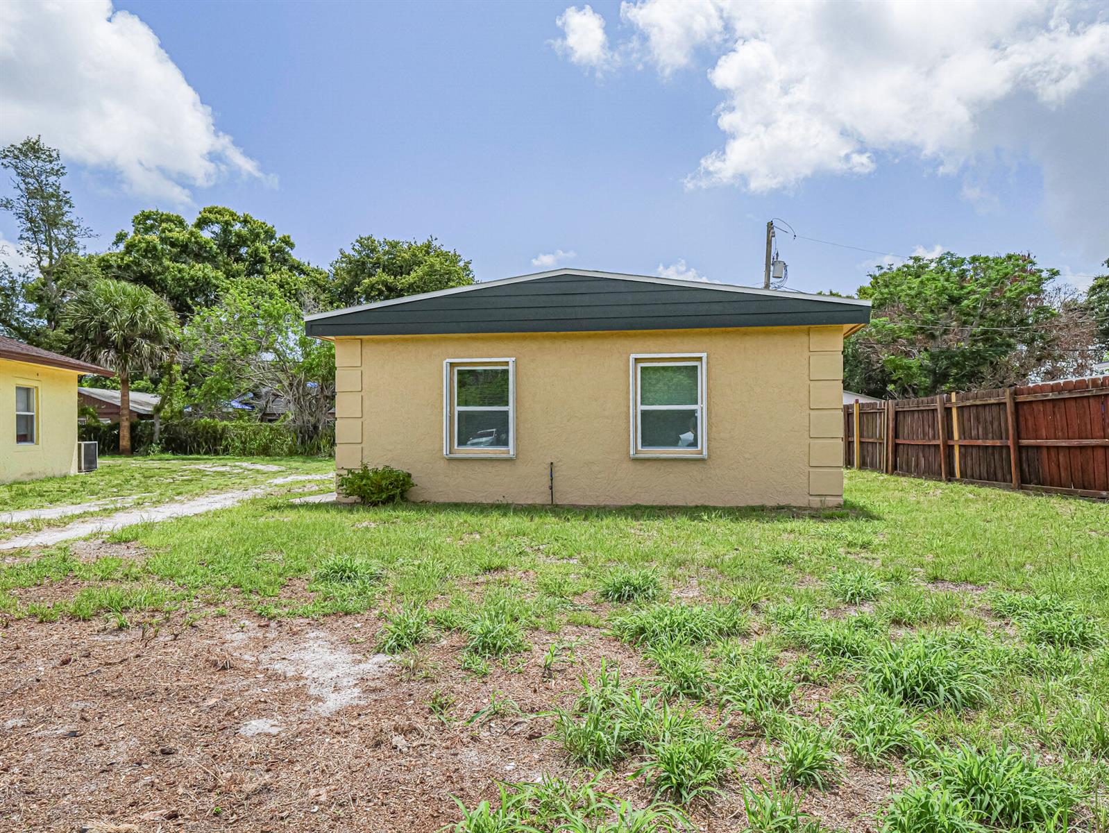A yellow single-story house with two windows sits on a grassy lot with a fence — 4716 29th Avenue, Vero Beach FL 32967, VERO BEACH, FL