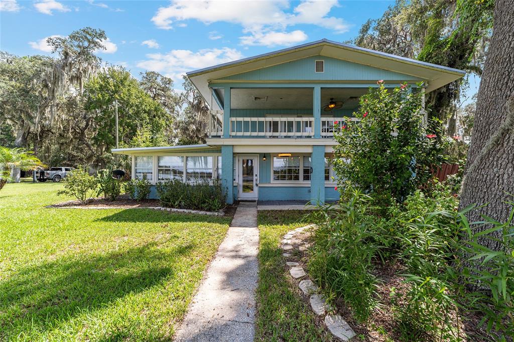 A two-story blue house with a balcony and a concrete walkway leading to the entrance — 10399 NE 218TH LANE ROAD, FORT MC COY, FL