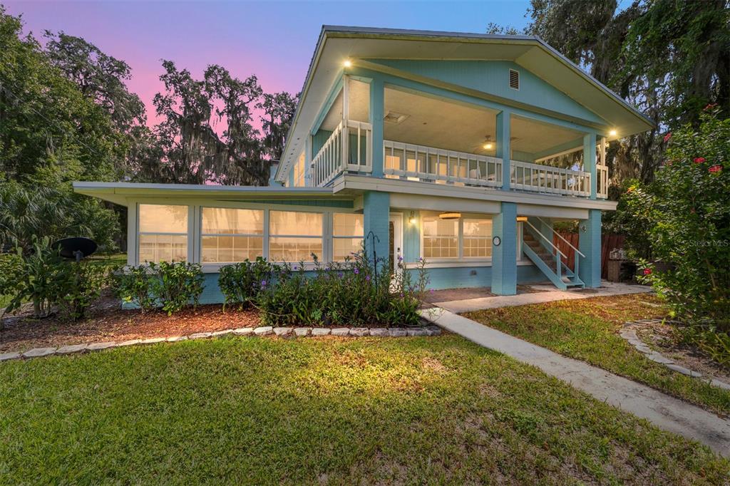 A two-story light blue house with a screened-in porch and an upper-level balcony — 10399 NE 218TH LANE ROAD, FORT MC COY, FL