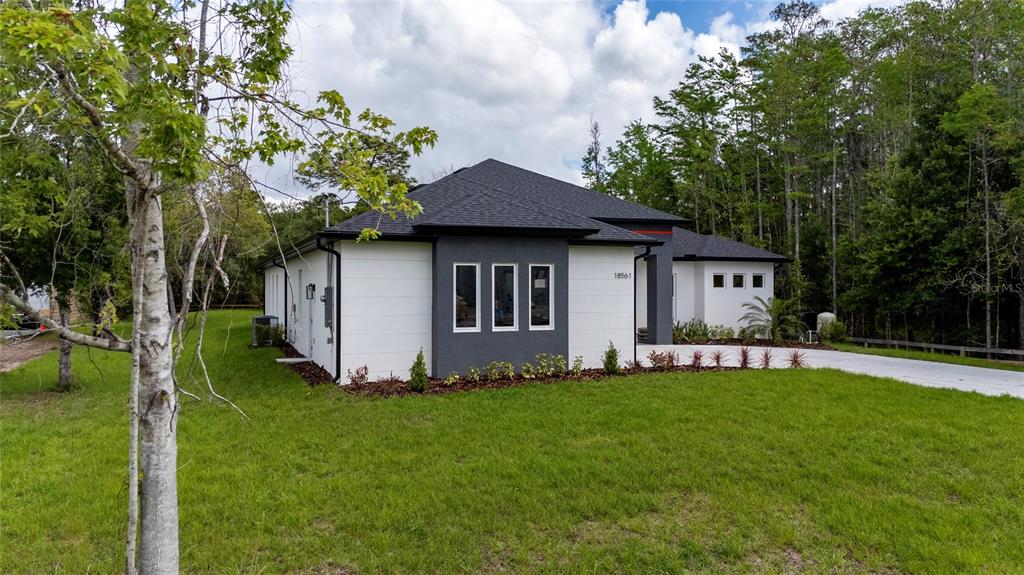 A modern single-story house with white and dark gray exterior walls sits on a lawn — 18561 SABAL STREET, ORLANDO, FL