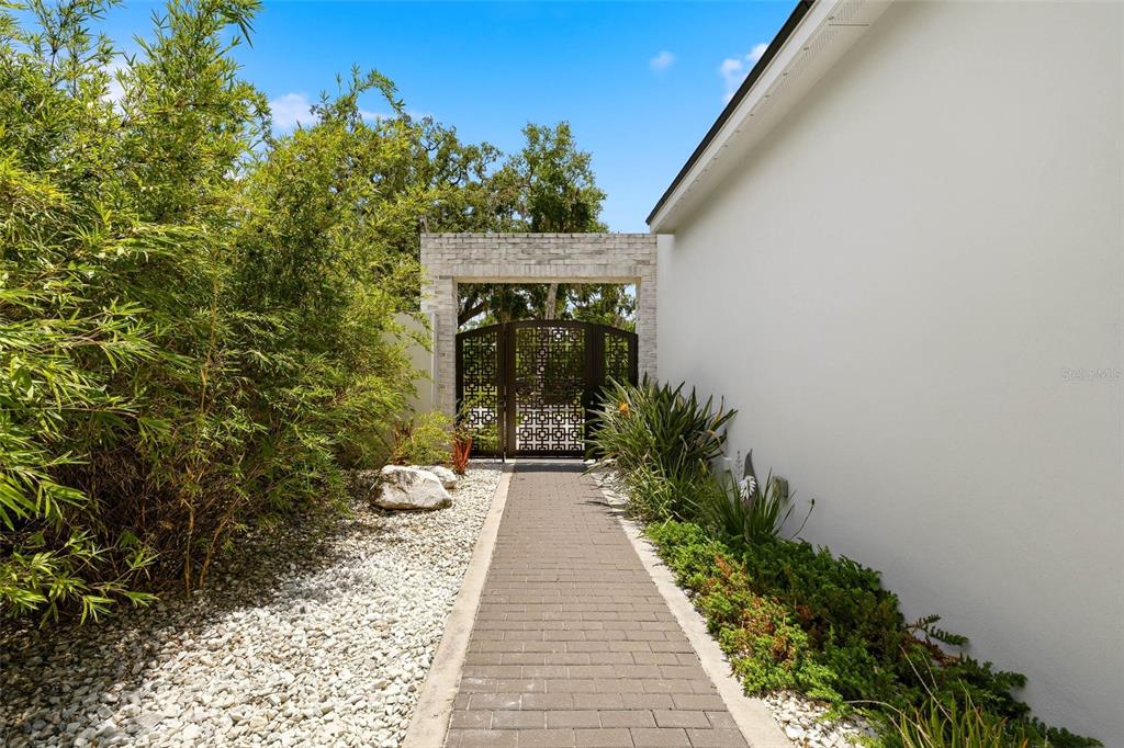 A stone walkway leads to a decorative metal gate framed by a white stone archway — 723 SYMONDS AVENUE, WINTER PARK, FL