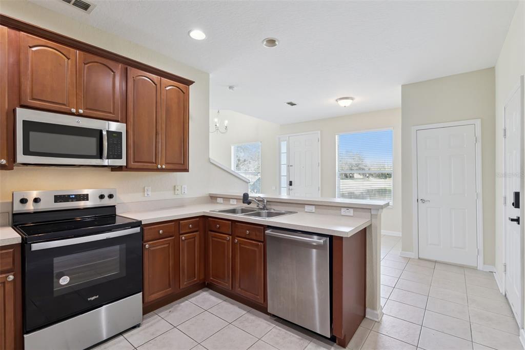 A kitchen with wood cabinets, stainless steel appliances, and a breakfast bar overlooking the entryway — 1431 SHALLCROSS AVENUE, ORLANDO, FL