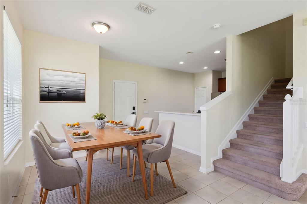 A dining area with a wooden table and chairs sits beside a carpeted staircase — 1431 SHALLCROSS AVENUE, ORLANDO, FL