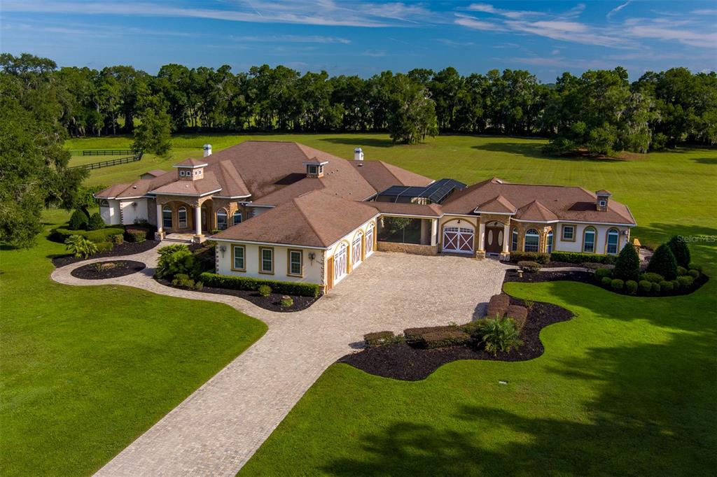 An aerial view of a large, single-story suburban house with a paved driveway and lawn — 6853 NW 12TH STREET, OCALA, FL