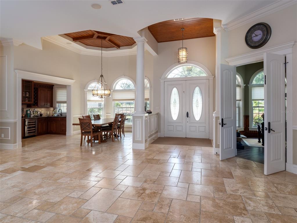A spacious foyer with travertine tile floors leads to a dining area and front entrance — 6853 NW 12TH STREET, OCALA, FL