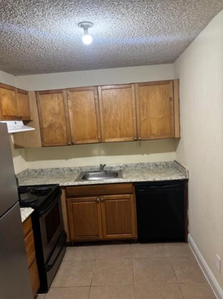 A kitchen features wood cabinets, a stainless steel sink, black appliances, and tiled flooring — 1205 Meadows Circle, Boynton Beach FL 33436, BOYNTON BEACH, FL