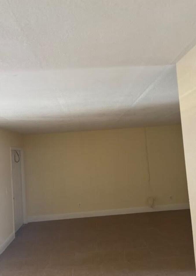 An empty room with beige walls, white trim, and light-colored tile flooring — 1205 Meadows Circle, Boynton Beach FL 33436, BOYNTON BEACH, FL