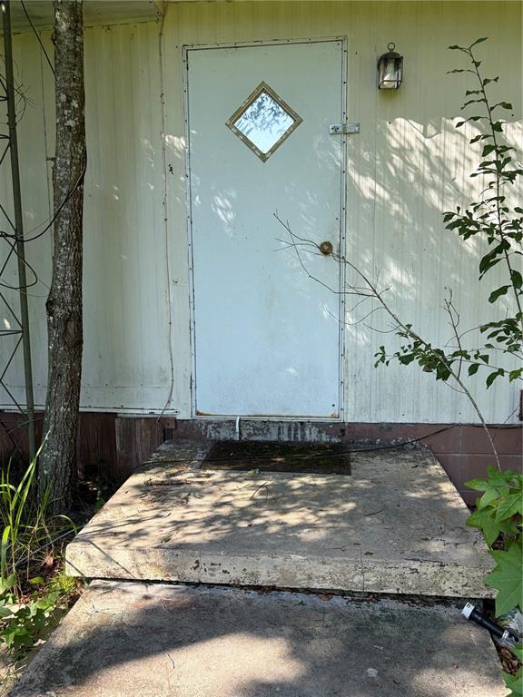 A weathered mobile home sits in a wooded, grassy lot surrounded by tall trees — 2361 NE 115TH AVENUE, SILVER SPRINGS, FL
