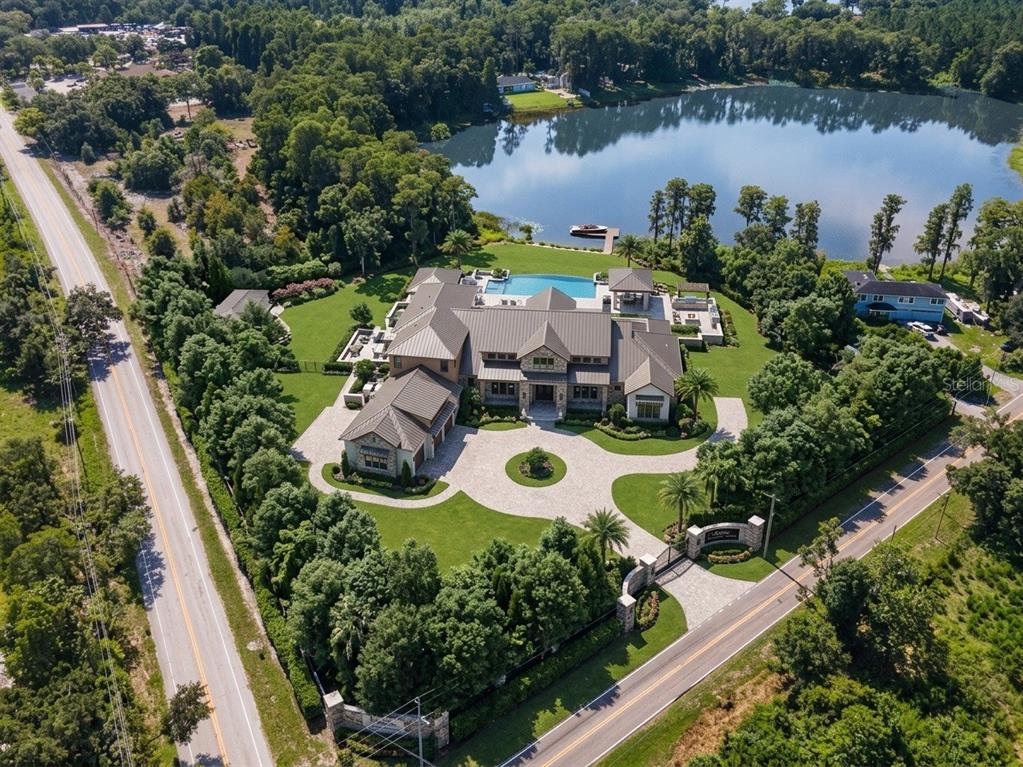An aerial view shows a large estate with a pool, lakefront access, and circular driveway — 18117 BOY SCOUT ROAD, ODESSA, FL