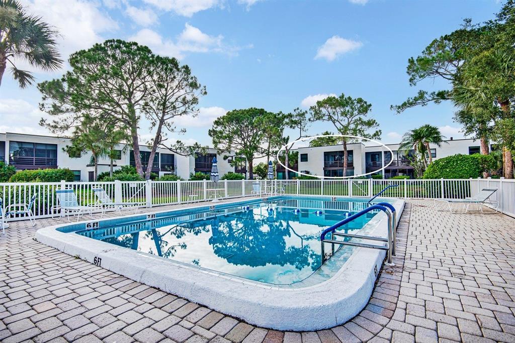 A swimming pool with a white fence and multi-story apartment buildings in the background — 5030 MARSH FIELD ROAD UNIT 22, SARASOTA, FL