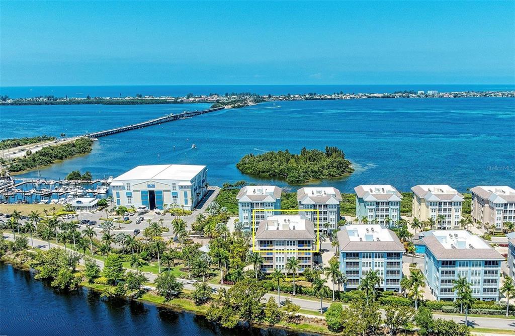 An aerial view shows a multi-story residential building highlighted by a yellow box near water — 395 ARUBA CIRCLE UNIT 402, BRADENTON, FL