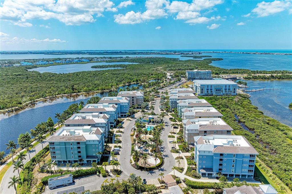 Aerial view of a coastal apartment complex surrounded by water and lush vegetation — 395 ARUBA CIRCLE UNIT 402, BRADENTON, FL