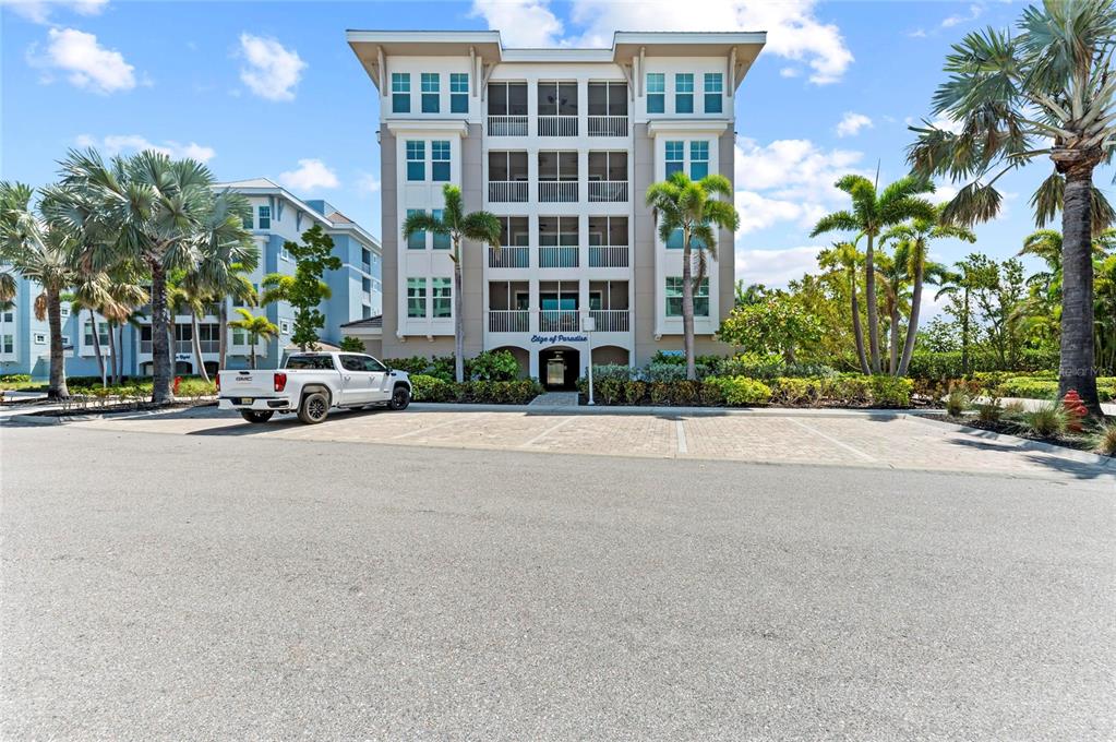 A white pickup truck is parked in front of a four-story residential building with balconies — 395 ARUBA CIRCLE UNIT 402, BRADENTON, FL
