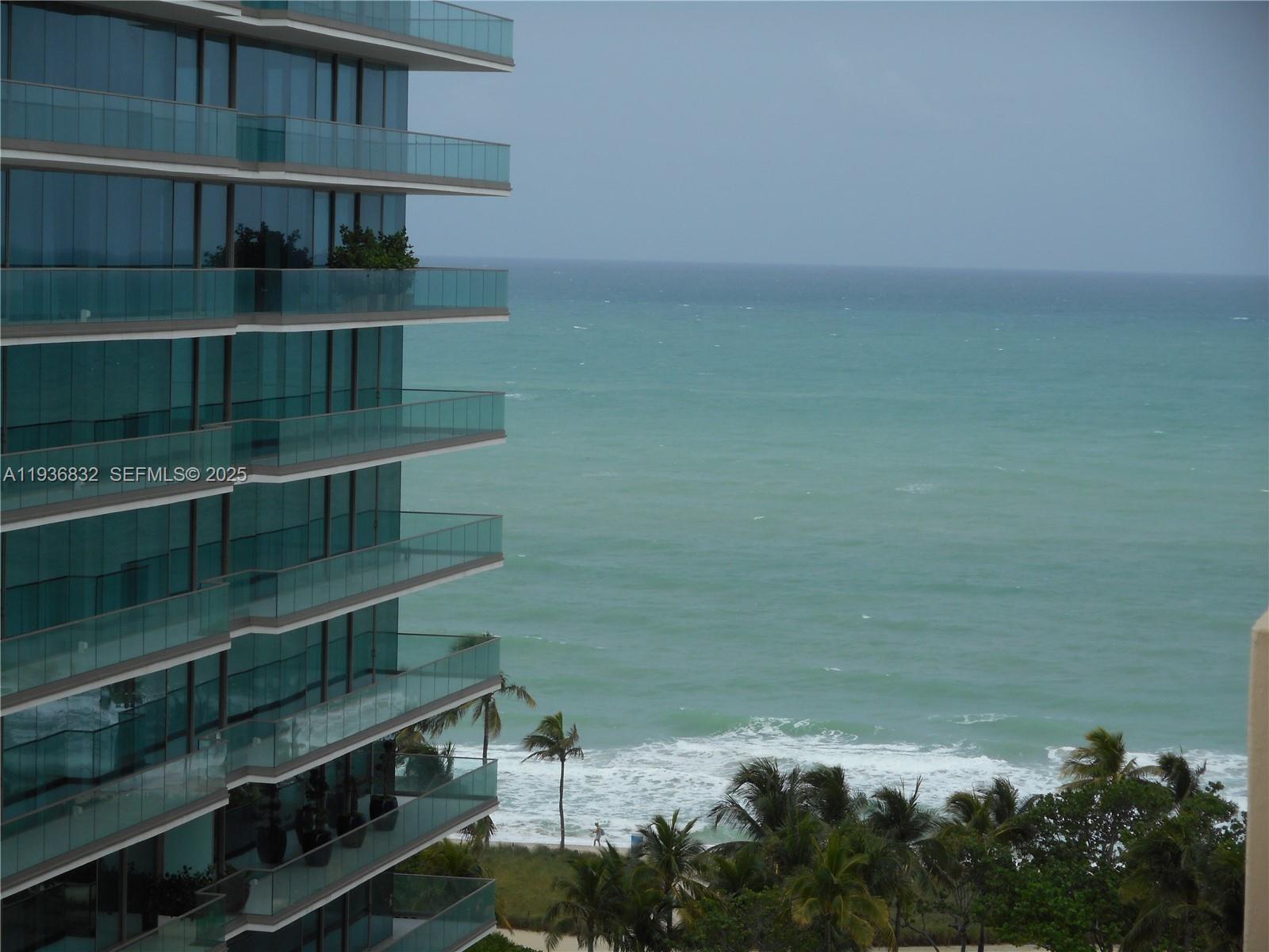 A modern high-rise building overlooks the ocean with palm trees on the beach below — 10185 Collins Ave # 1204, Bal Harbour FL 33154, BAL HARBOUR, FL
