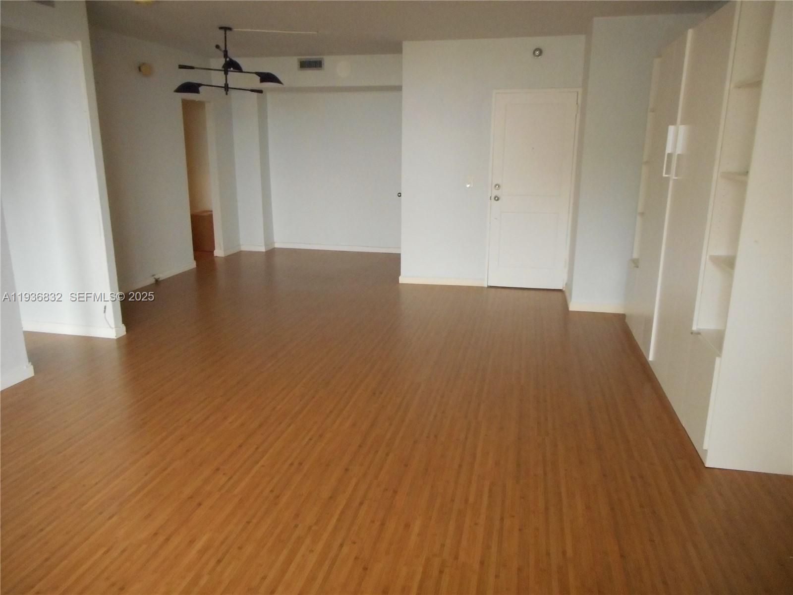An empty room features light wood-look flooring, white walls, a ceiling fan, and built-in shelving — 10185 Collins Ave # 1204, Bal Harbour FL 33154, BAL HARBOUR, FL