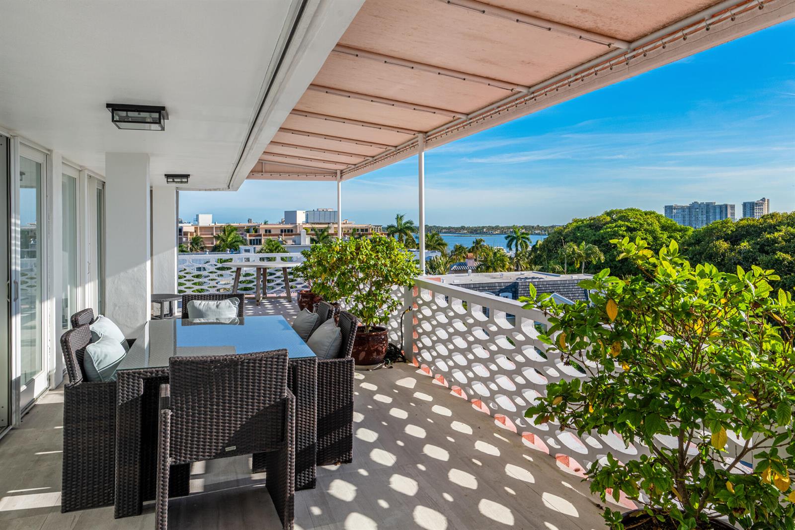 A balcony with wicker dining furniture, a retractable awning, and a view of the water — 315 S Lake Drive # D, Palm Beach FL 33480, PALM BEACH, FL