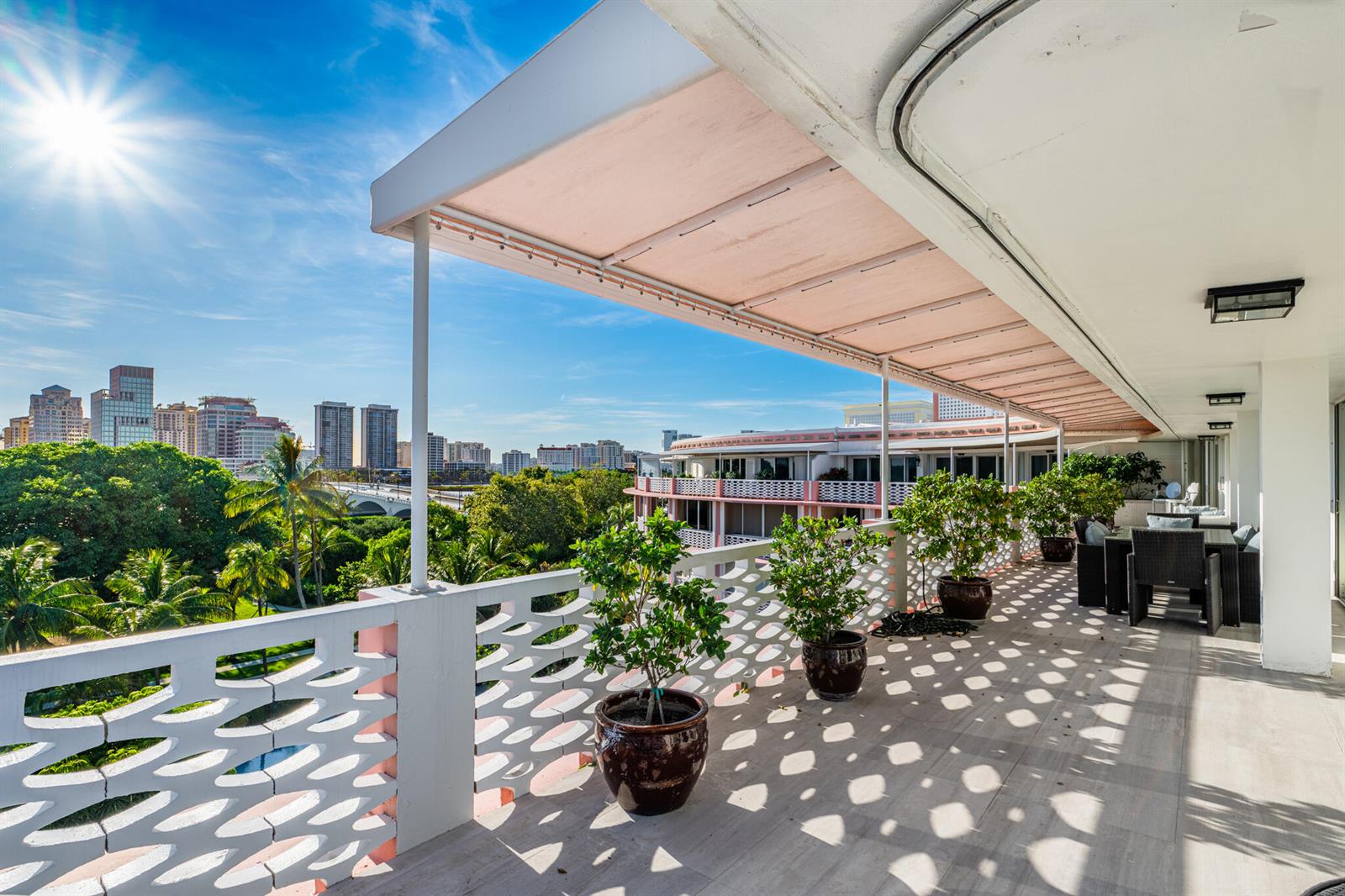 A balcony with potted plants, a patterned railing, and an awning overlooks a city skyline — 315 S Lake Drive # D, Palm Beach FL 33480, PALM BEACH, FL